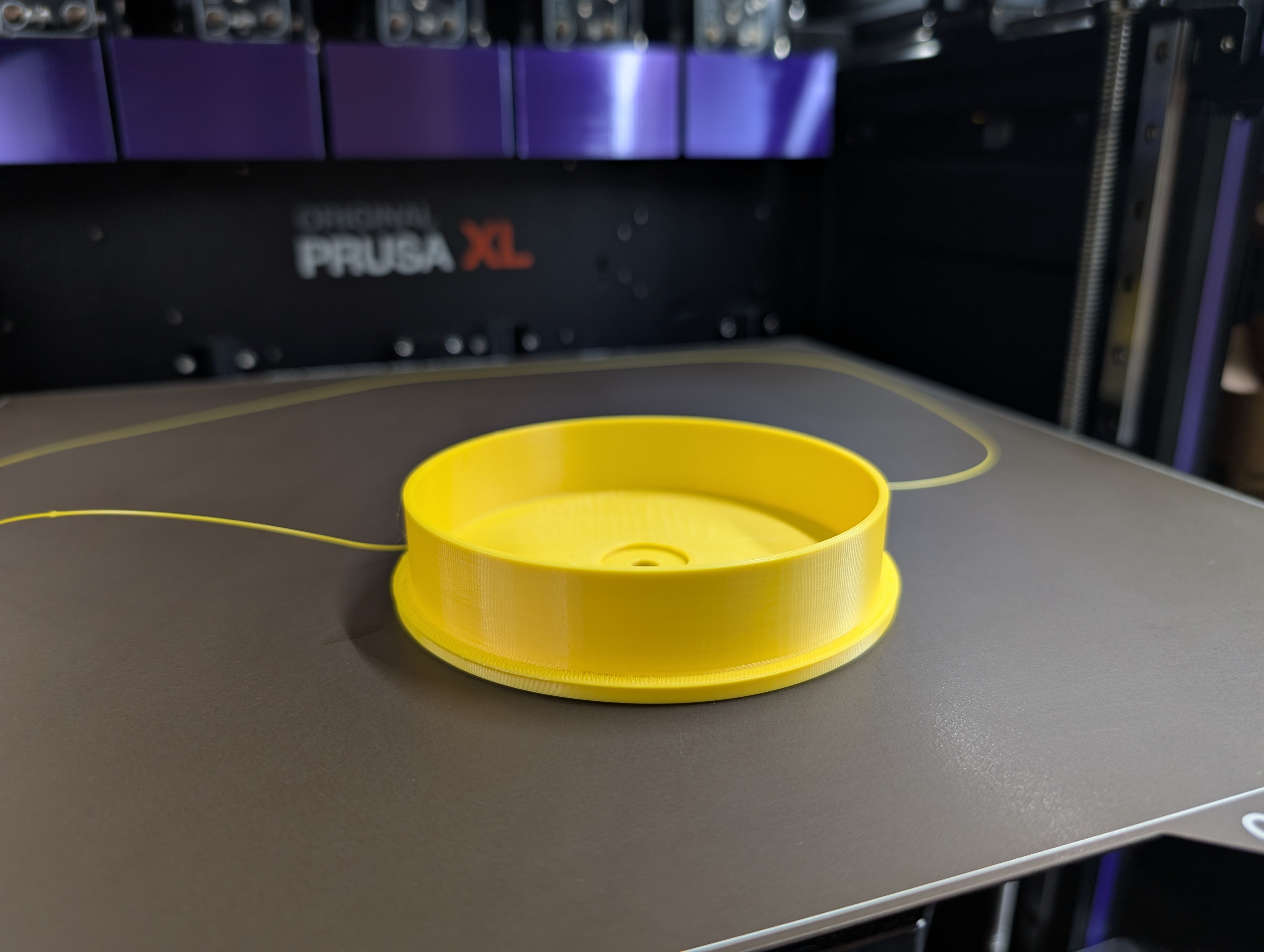 Yellow 3D printed circular float fresh off the Prusa XL